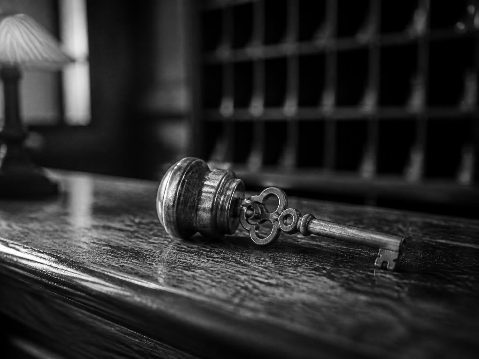 Chiave di camera in ottone con pendaglio su bancone di legno della reception, fotografia in bianco e nero