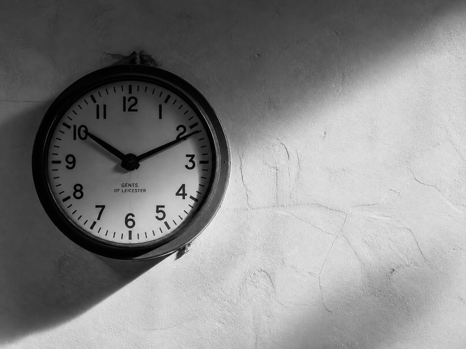Orologio da stazione su parete intonacata, fotografia in bianco e nero