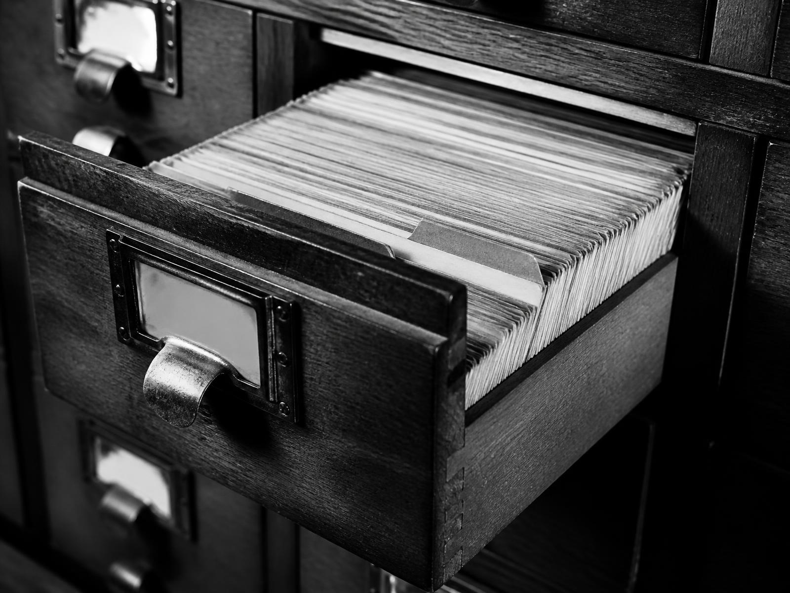 Cassettiera di schede catalogo aperta con schede ordinate, fotografia in bianco e nero